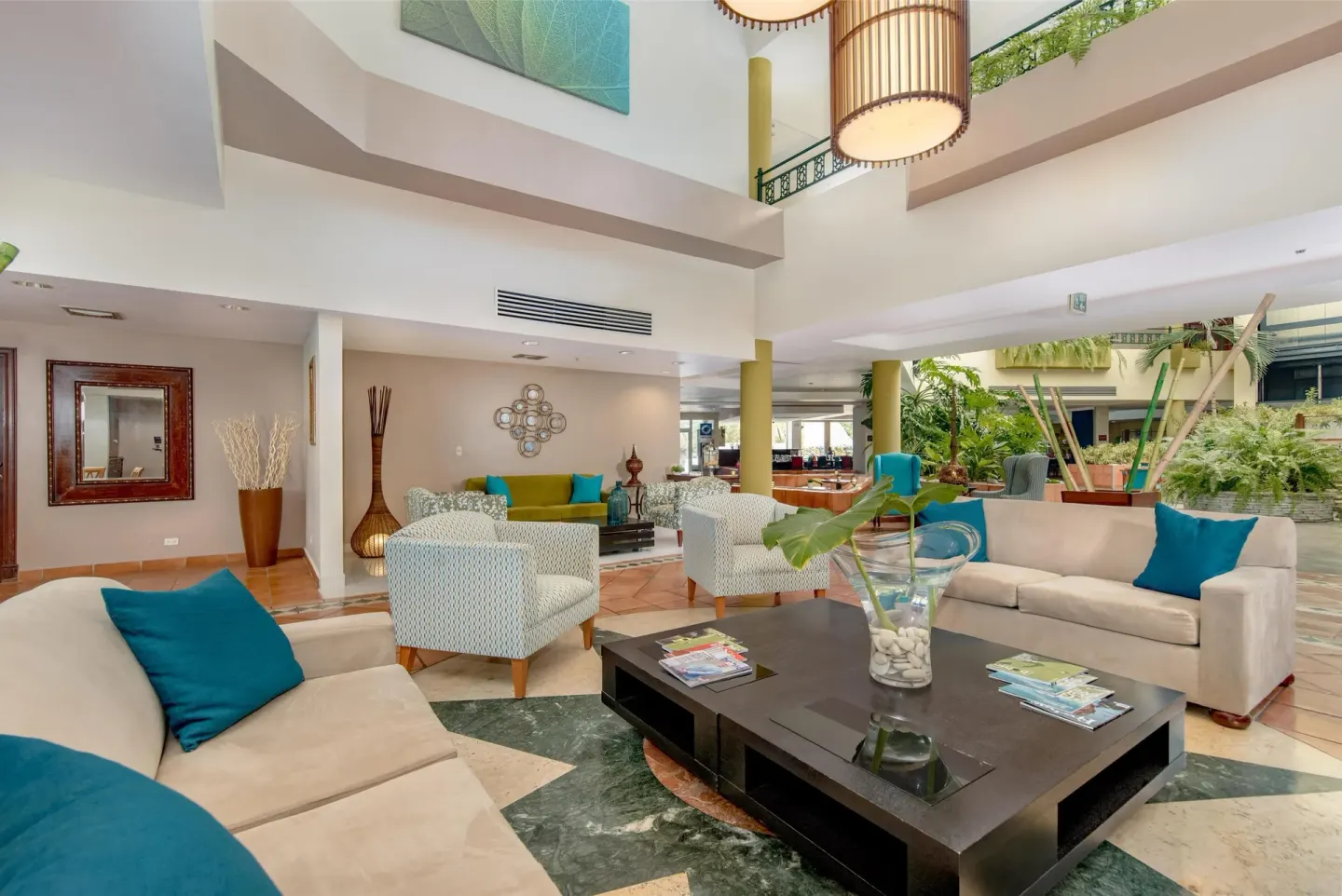 Lobby lounge with sofas and teal pillows at Hodelpa Garden Suites Golf & Convention Center.