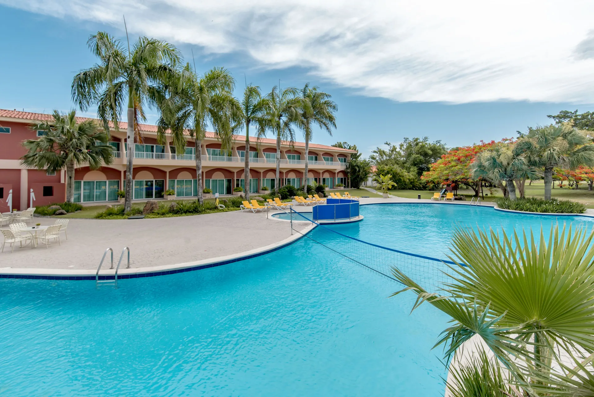 Large outdoor pool and guest-room building at Hodelpa Garden Suites Golf & Convention Center.