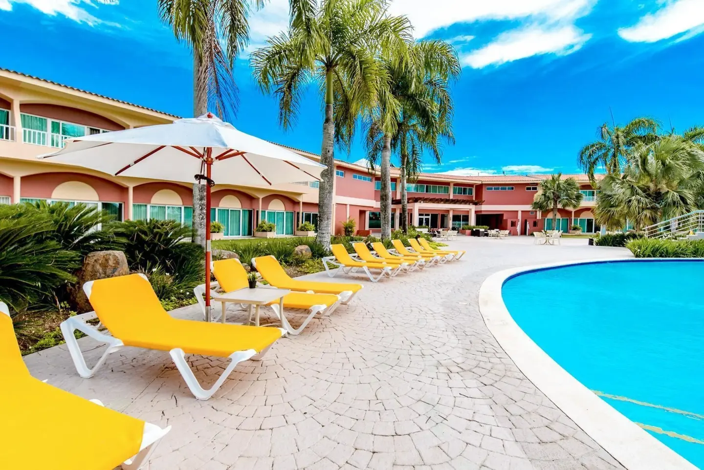 Yellow lounge chairs beside the pool at Hodelpa Garden Suites Golf & Convention Center.