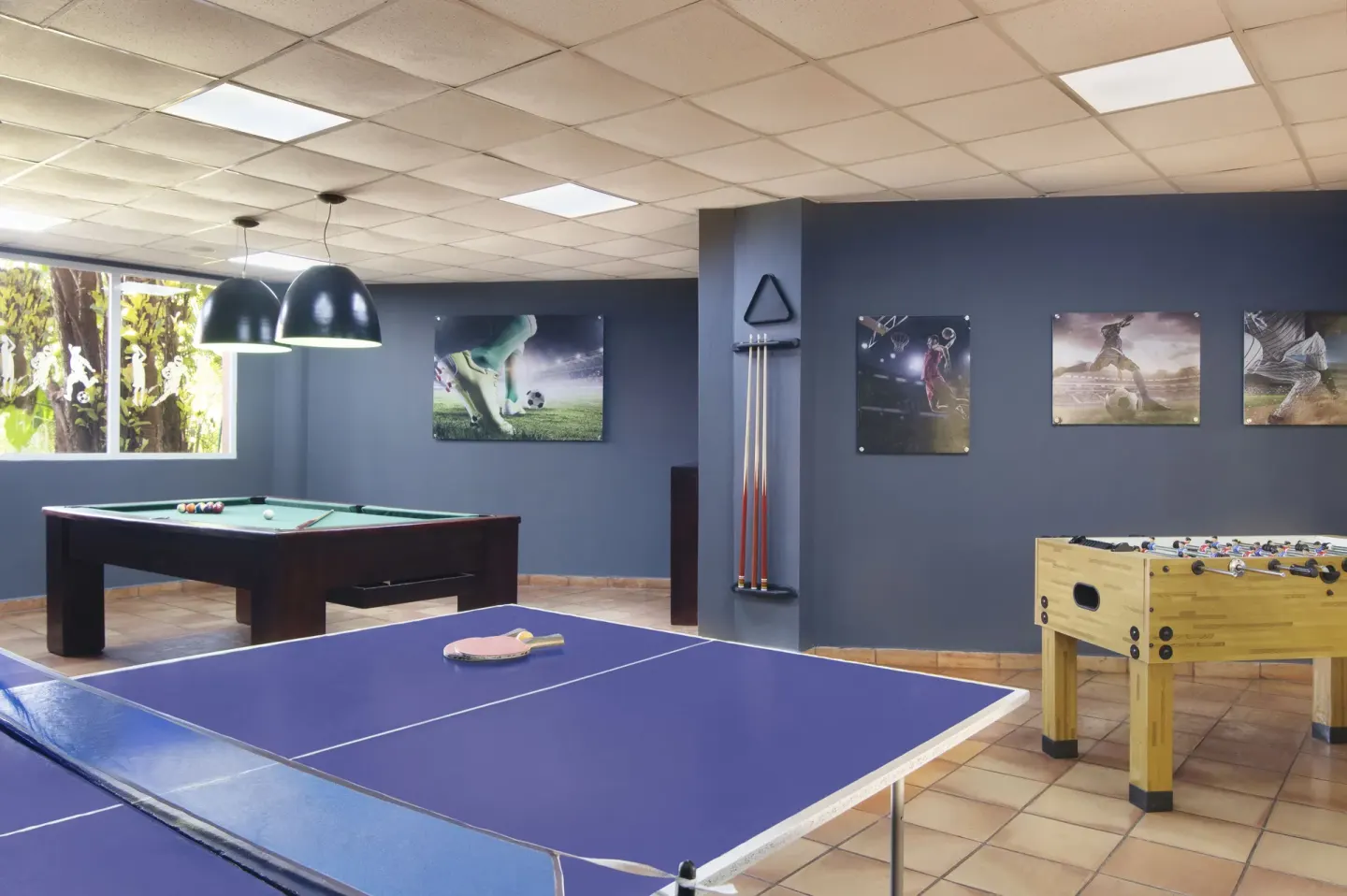 A recreation room with ping-pong, pool, and foosball at Hodelpa Garden Suites Golf & Convention Center.