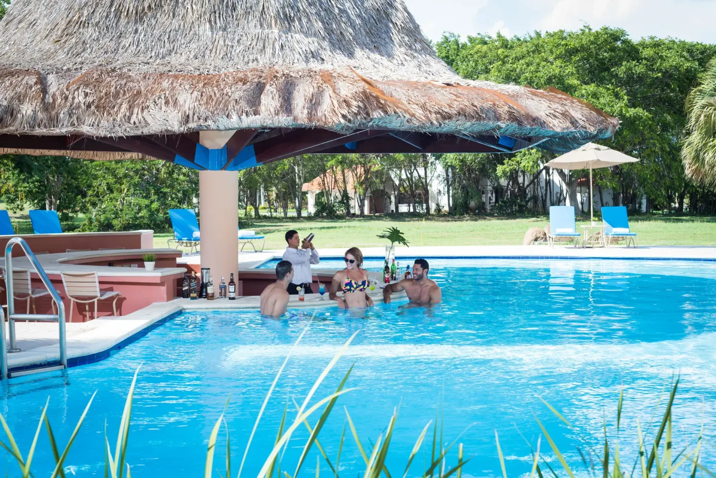 Poolside bar with guests at Hodelpa Garden Suites Golf & Convention Center.