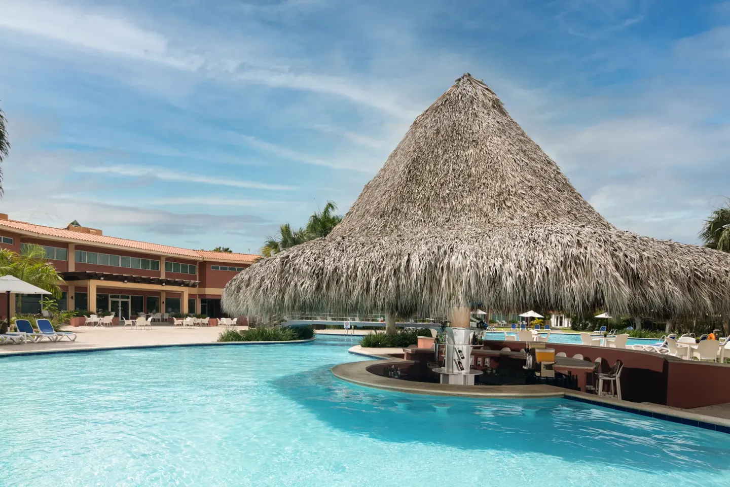 Thatched swim-up bar and pool at Hodelpa Garden Suites Golf & Convention Center.