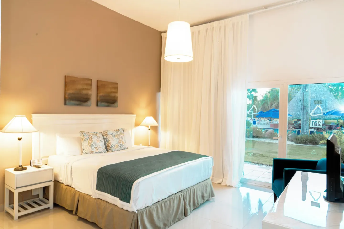 Family Suite king bed and glass doors at Hodelpa Garden Suites Golf & Convention Center.
