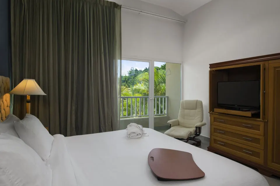 Royal Suite king bedroom with balcony view at Hodelpa Garden Suites Golf & Convention Center.