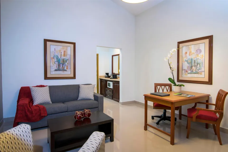 Royal Suite living area with sofa and desk at Hodelpa Garden Suites Golf & Convention Center.