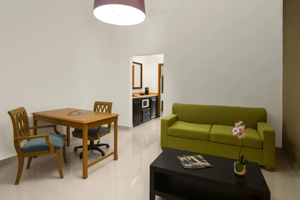 Suite living and dining area with kitchenette doorway at Hodelpa Garden Suites Golf & Convention Center.