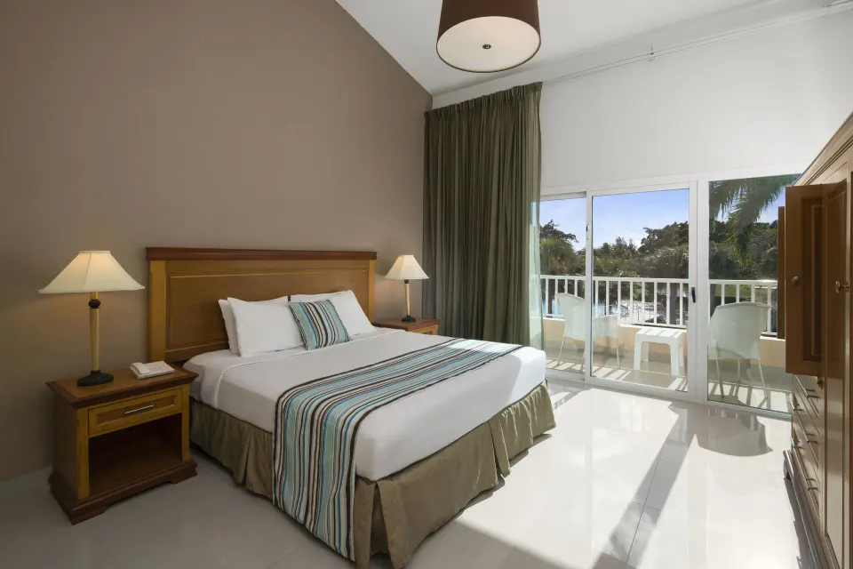 Suite Pool View king bedroom with balcony at Hodelpa Garden Suites Golf & Convention Center.