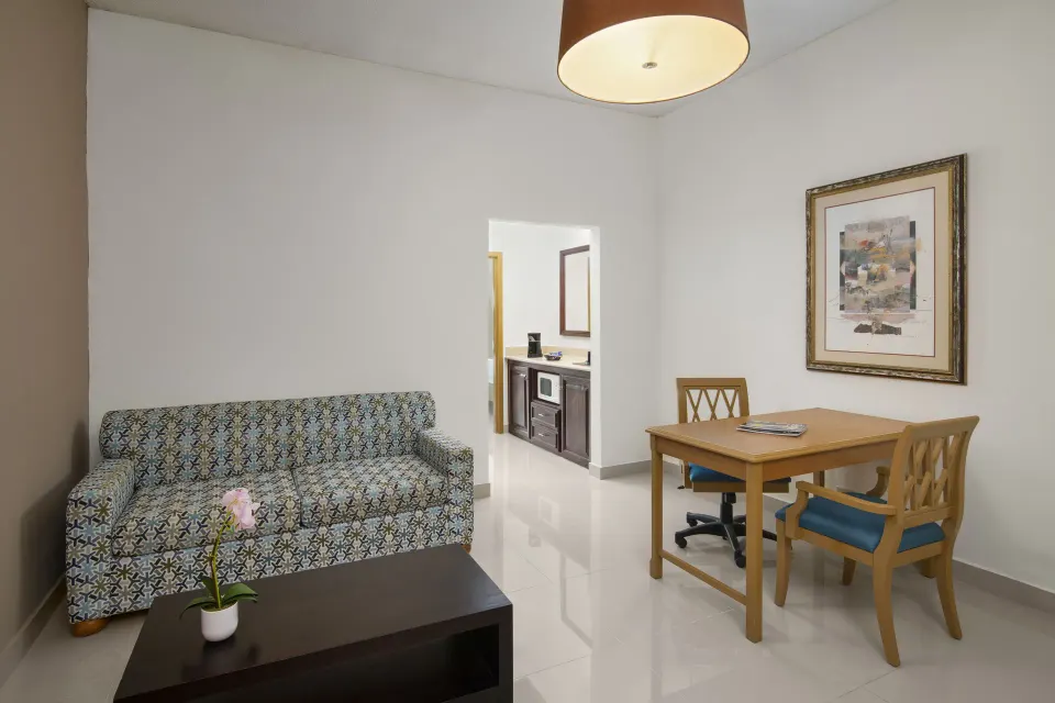 Suite Pool View living area with sofa and dining table at Hodelpa Garden Suites Golf & Convention Center.
