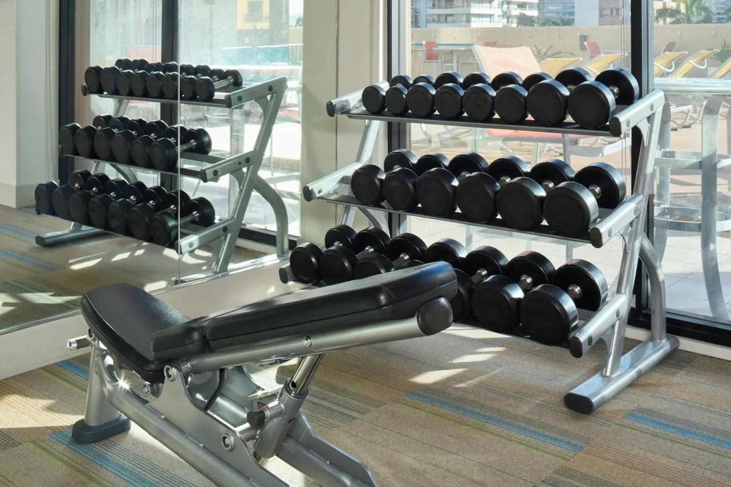 Dumbbell racks and an adjustable bench in the gym at Holiday Inn Express Waikiki.
