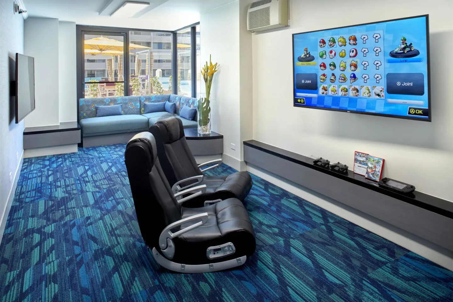 Game room with racing seats, large screen, and sofa at Holiday Inn Express Waikiki.