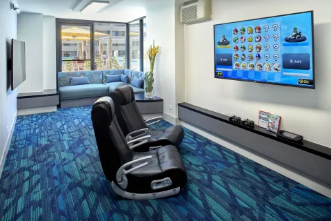 Game room with racing seats, large screen, and sofa at Holiday Inn Express Waikiki.