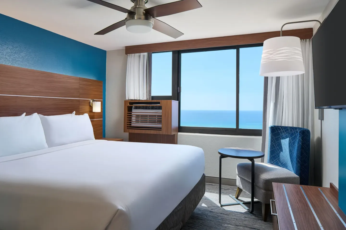 King bed guest room with ocean-facing window at Holiday Inn Express Waikiki.
