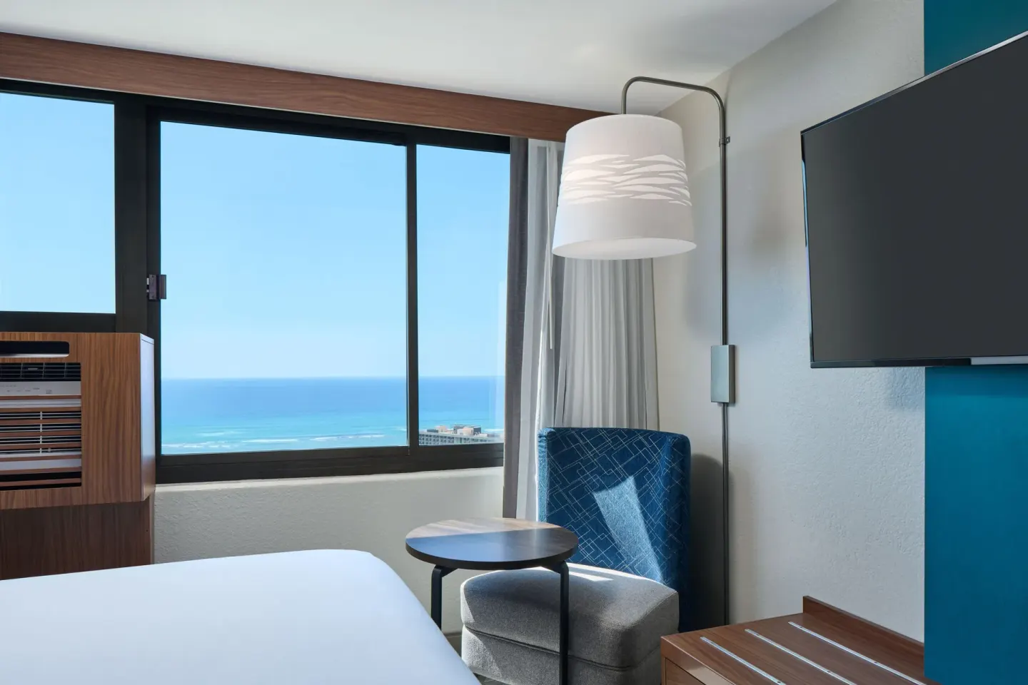 Guest room sitting area with ocean view window at Holiday Inn Express Waikiki.