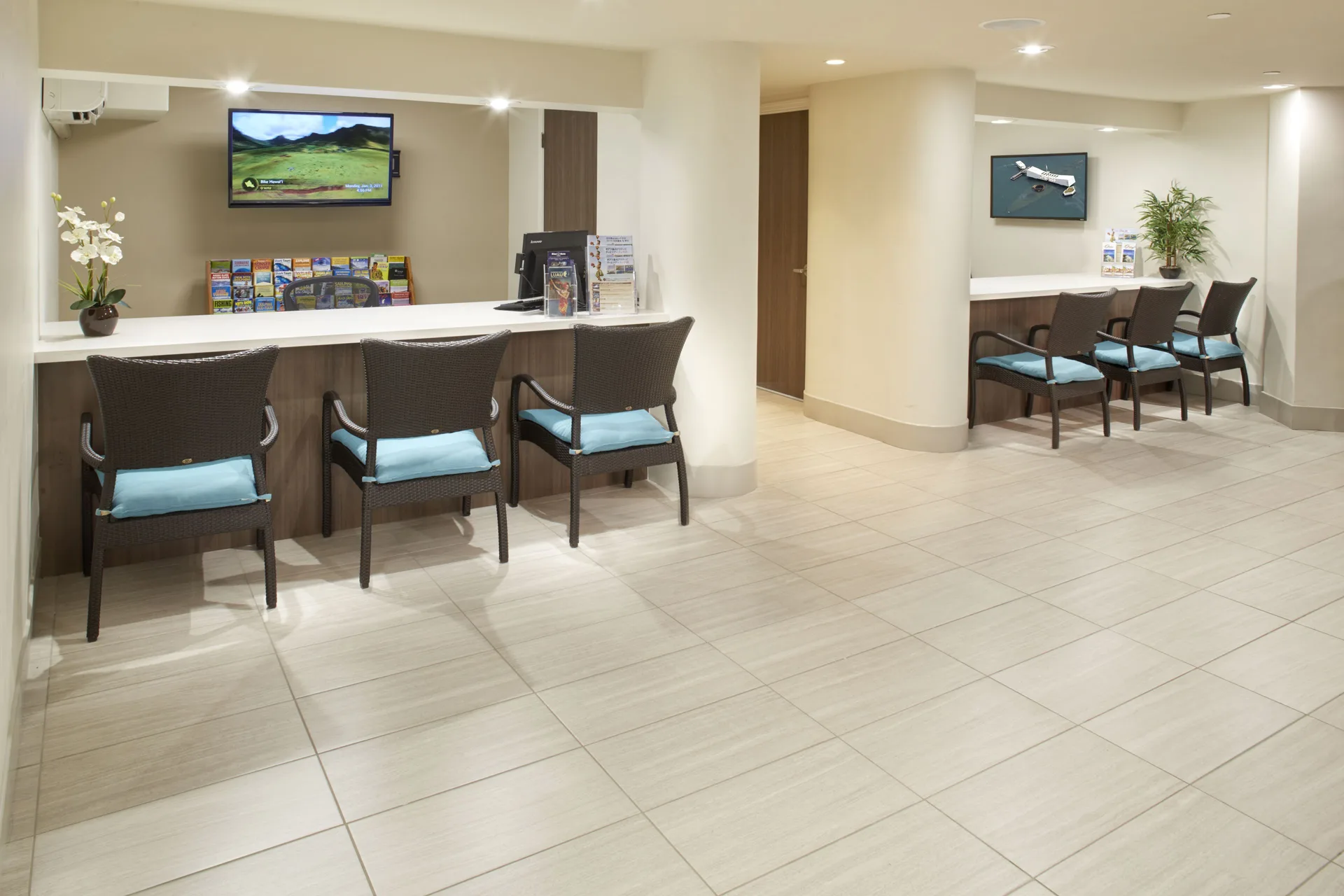Lobby seating area with chairs, counters, brochures, and wall screens at Holiday Inn Express Waikiki.