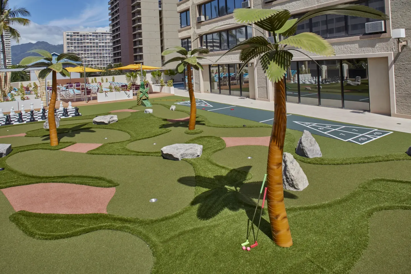 Mini golf course with palm decorations and shuffleboard courts at Holiday Inn Express Waikiki.