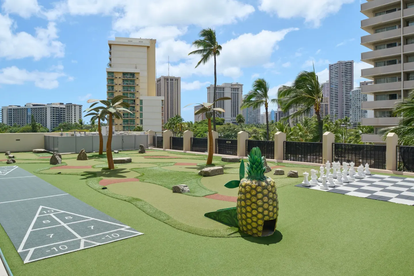 Outdoor game deck with mini golf, chess, and city buildings at Holiday Inn Express Waikiki.