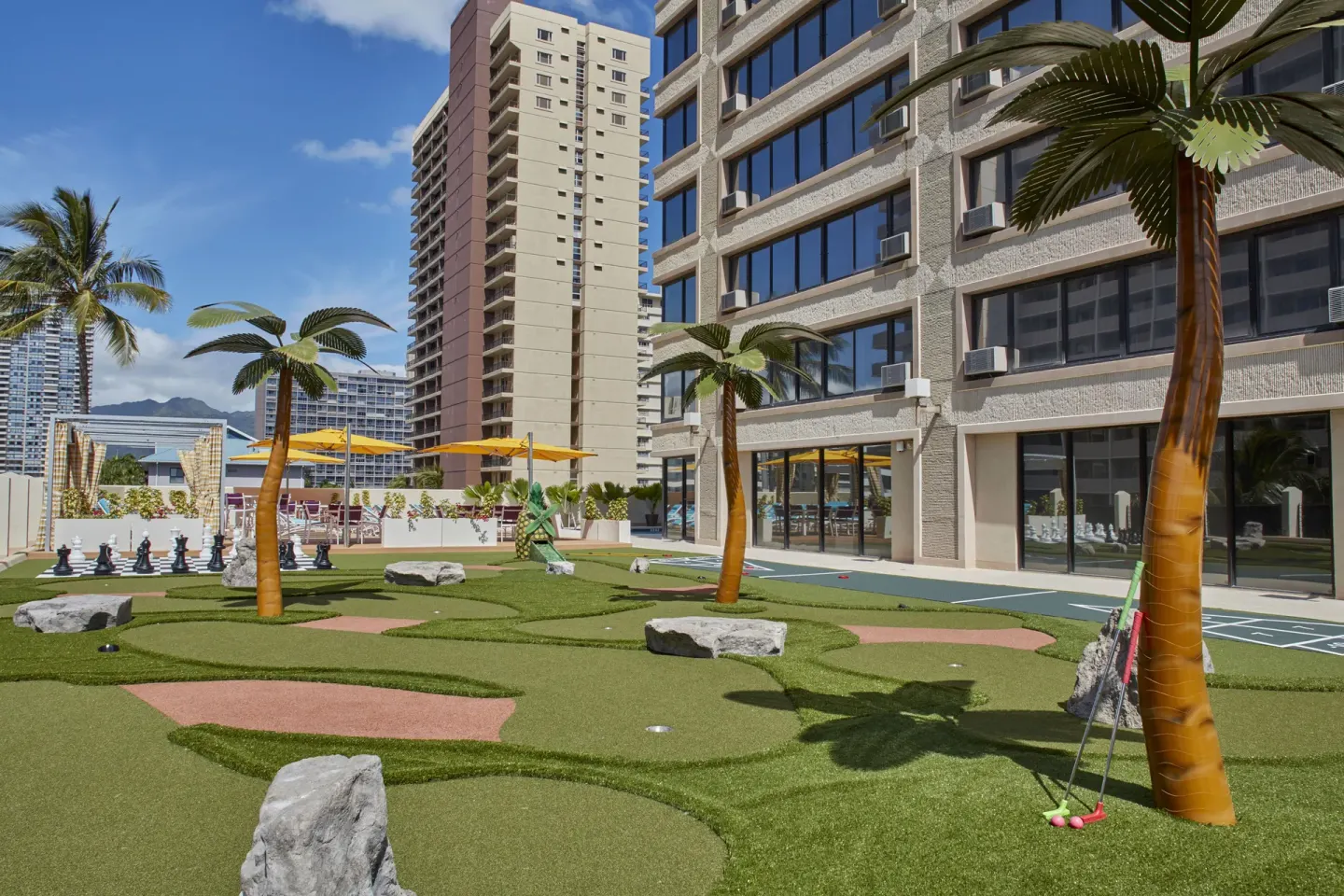 Mini golf putting area with artificial palms at Holiday Inn Express Waikiki.