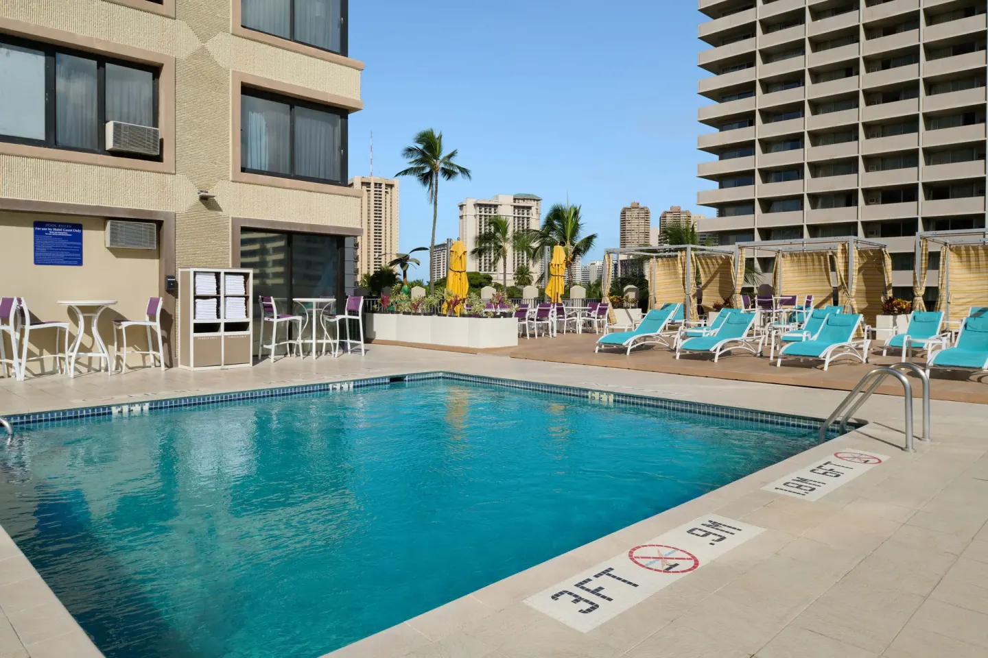 Outdoor pool deck with lounge chairs at Holiday Inn Express Waikiki.