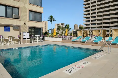 Outdoor pool deck with lounge chairs at Holiday Inn Express Waikiki.