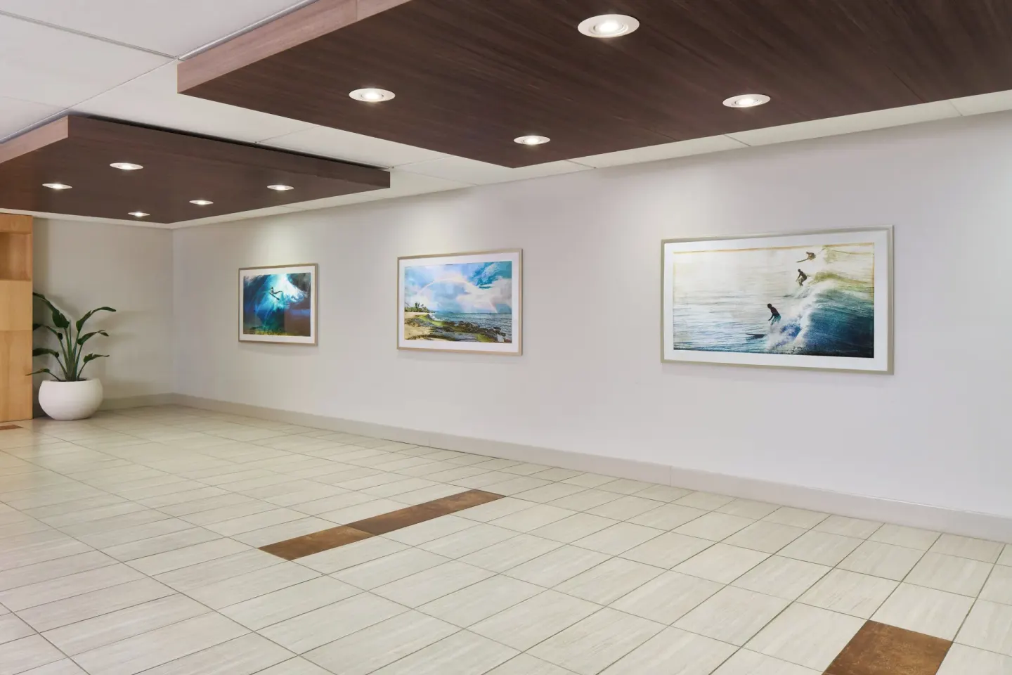 Corridor wall with framed ocean artwork and tiled floor at Holiday Inn Express Waikiki.