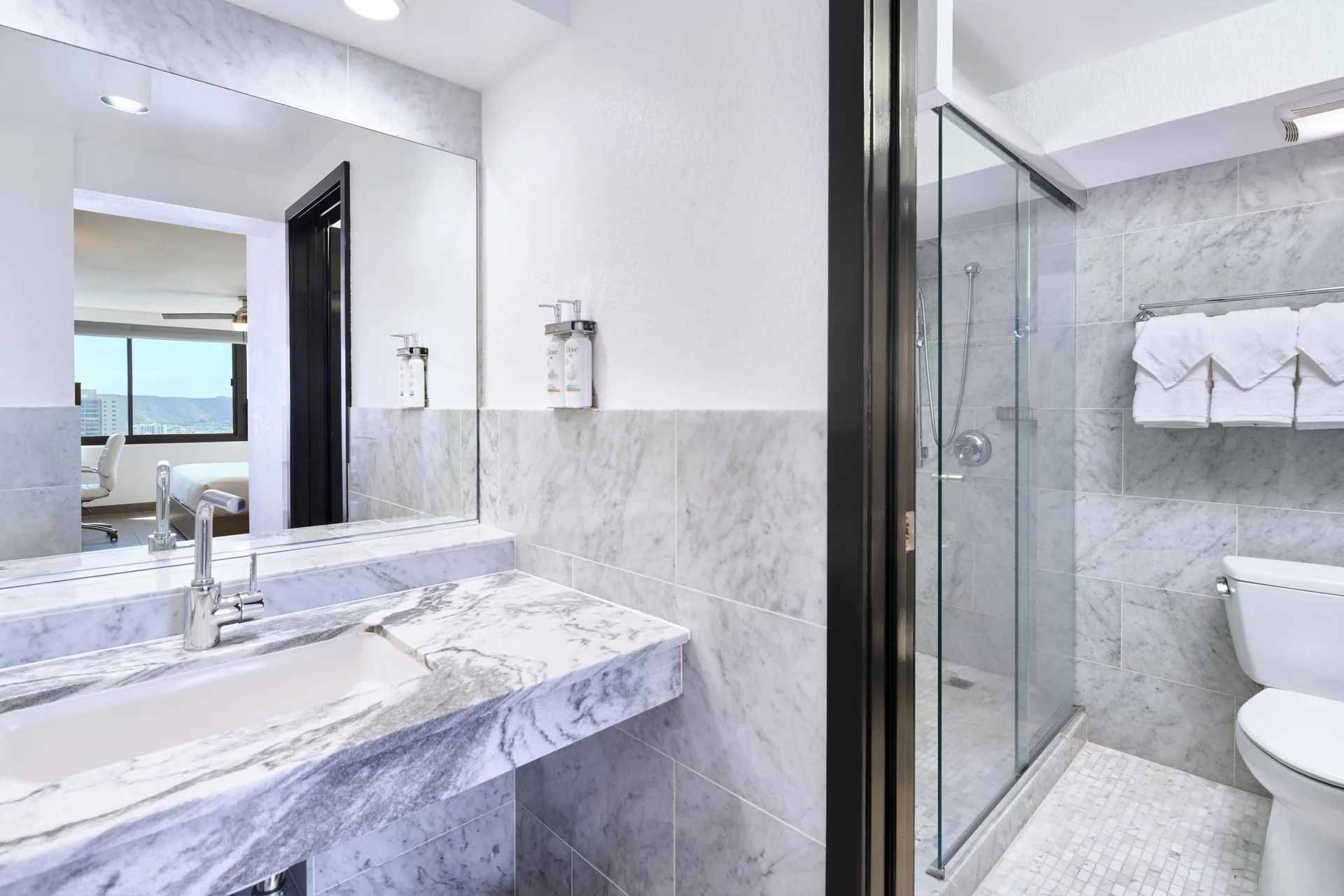 Deluxe Ocean View Room bathroom with marble vanity and glass shower at Holiday Inn Express Waikiki.