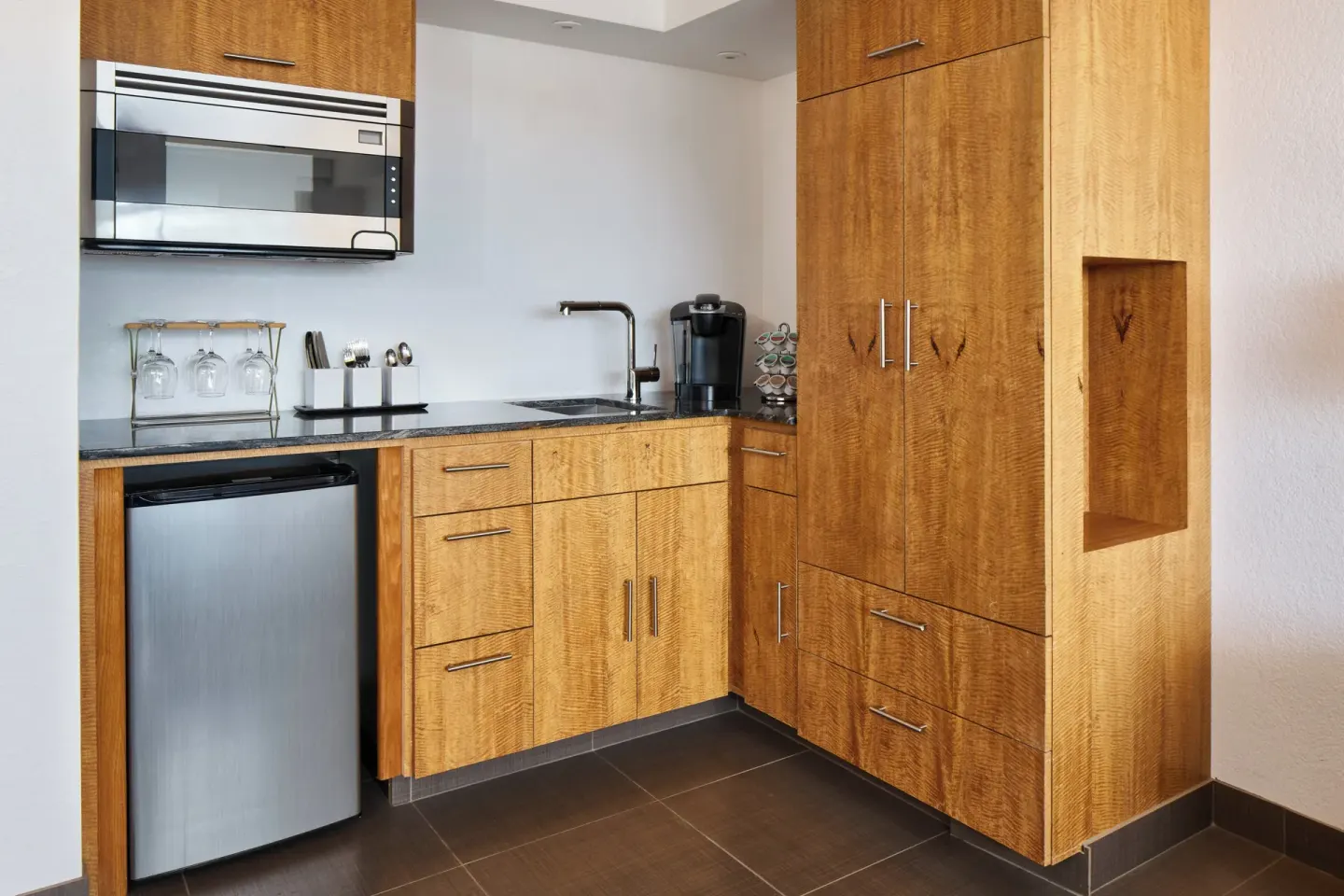 Deluxe Ocean View Room kitchenette with wood cabinetry at Holiday Inn Express Waikiki.