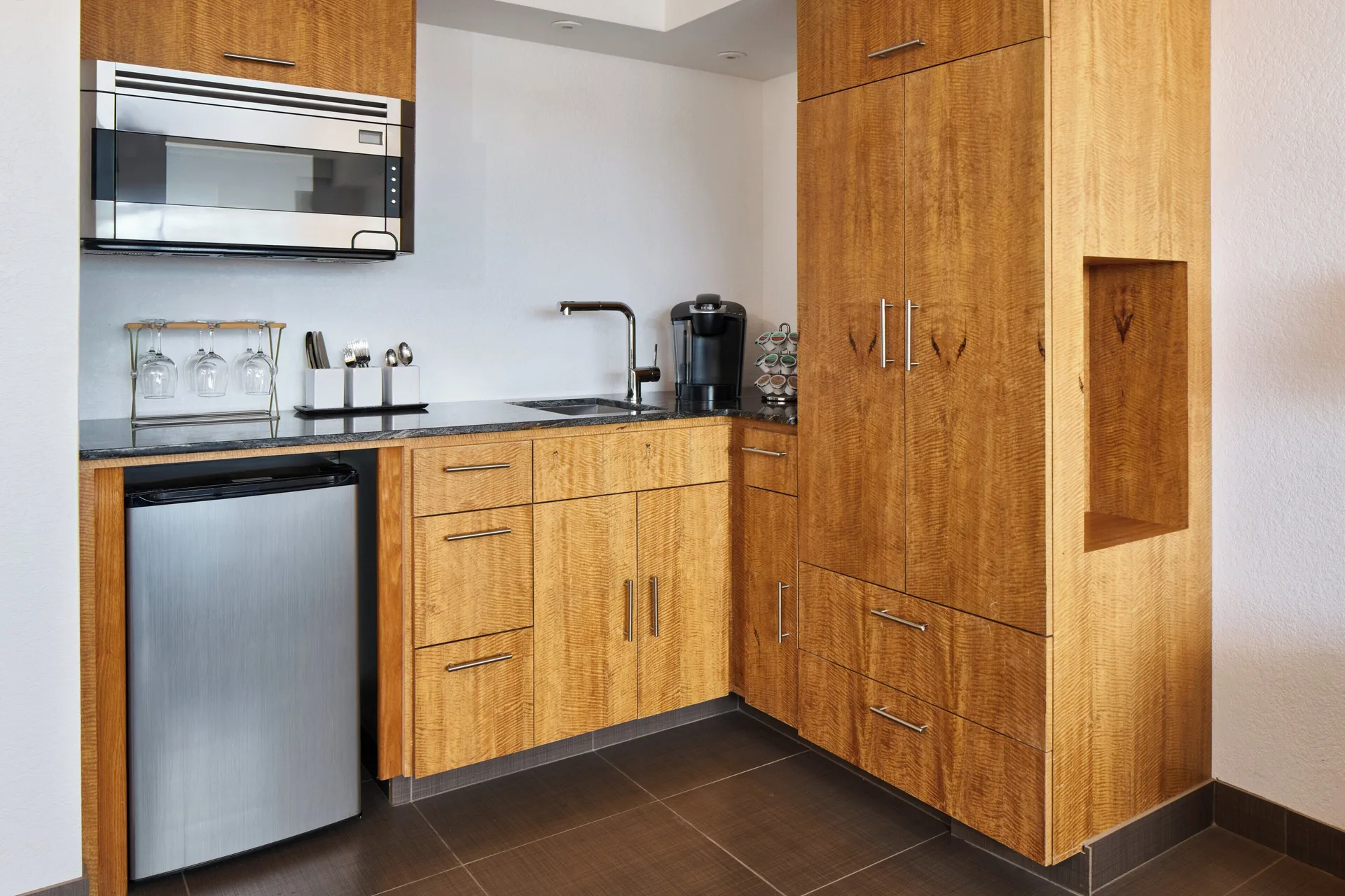 Deluxe Ocean View Room kitchenette with wood cabinetry at Holiday Inn Express Waikiki.