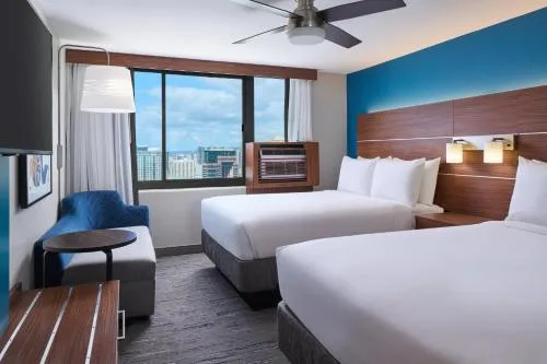 Two-bed guest room with blue accent wall at Holiday Inn Express Waikiki.