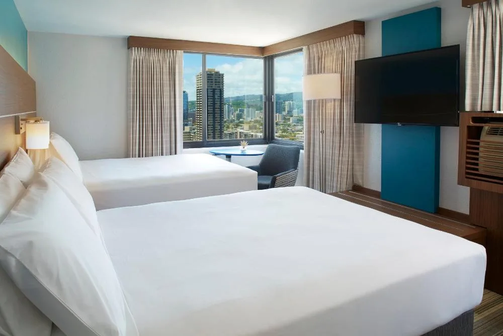 Two-bed standard accessible guest room with city-facing windows at Holiday Inn Express Waikiki.