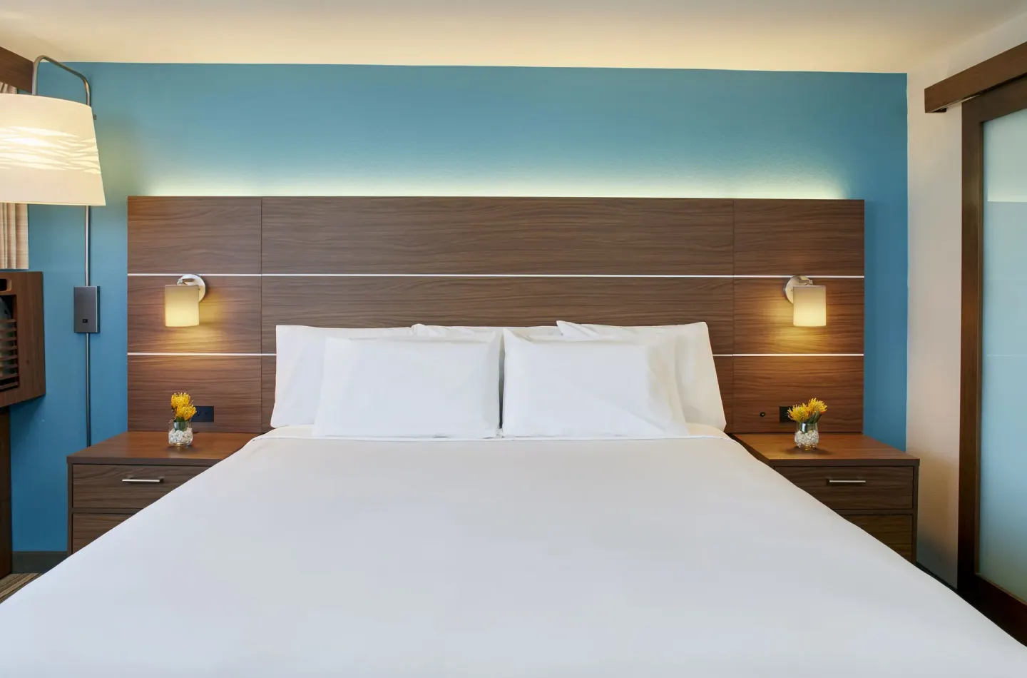 Standard Room king bed with wood headboard and blue wall at Holiday Inn Express Waikiki.