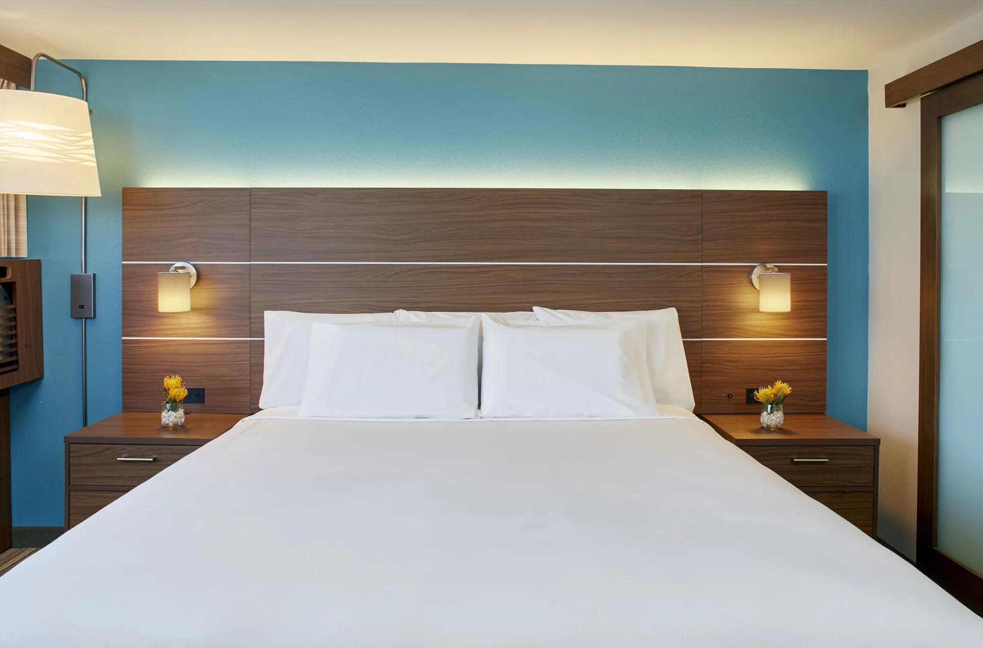 Standard Room king bed with wood headboard and blue wall at Holiday Inn Express Waikiki.