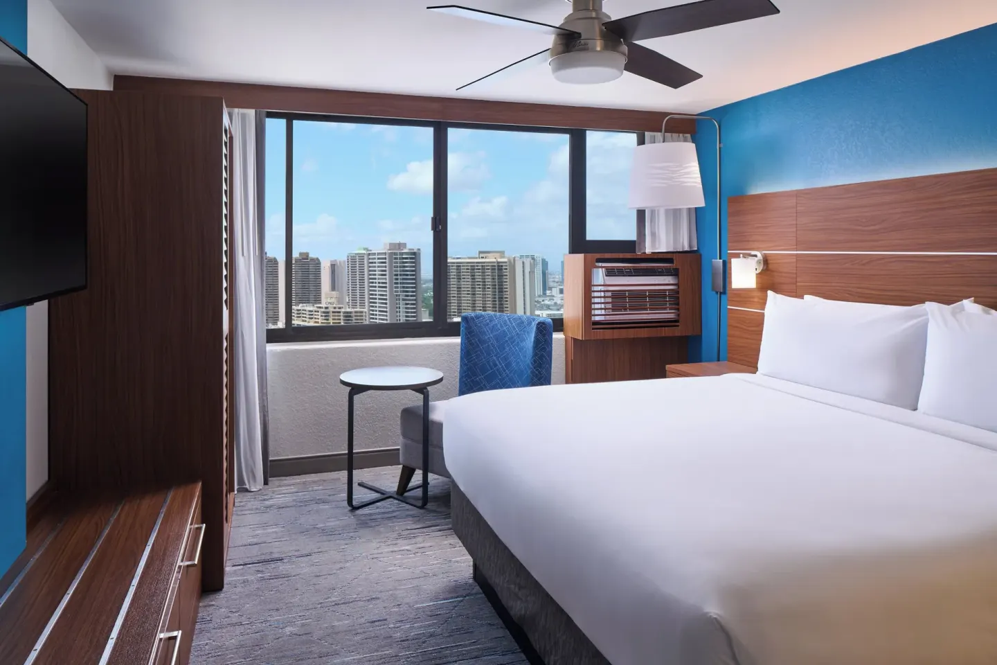 Standard Room king bed with city-facing window and seating nook at Holiday Inn Express Waikiki.