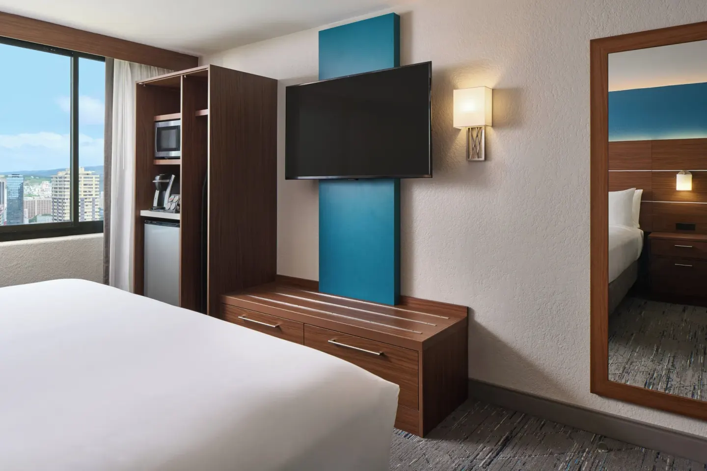 Standard Room king bed area with TV, storage, mirror, and window view at Holiday Inn Express Waikiki.