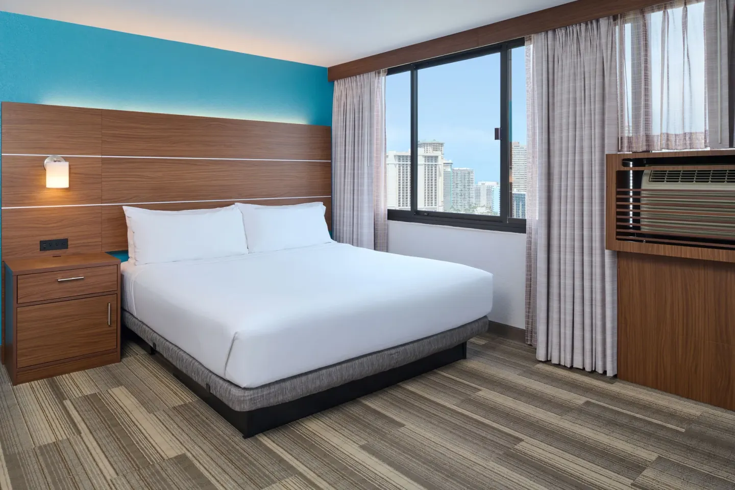 Standard Room king bed and city-facing window at Holiday Inn Express Waikiki.