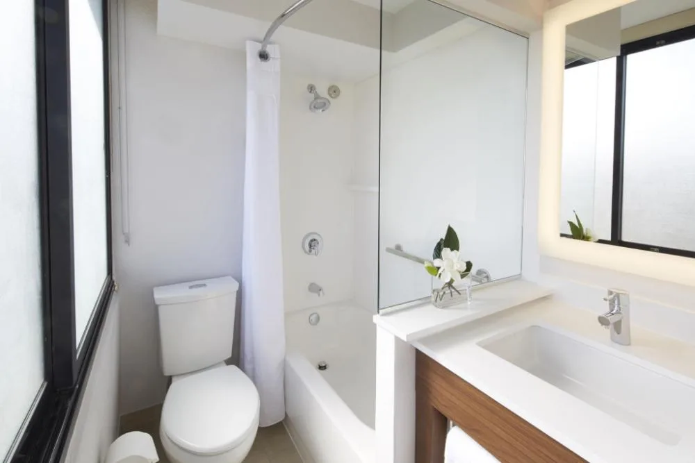 Standard room bathroom with tub shower and illuminated mirror at Holiday Inn Express Waikiki.