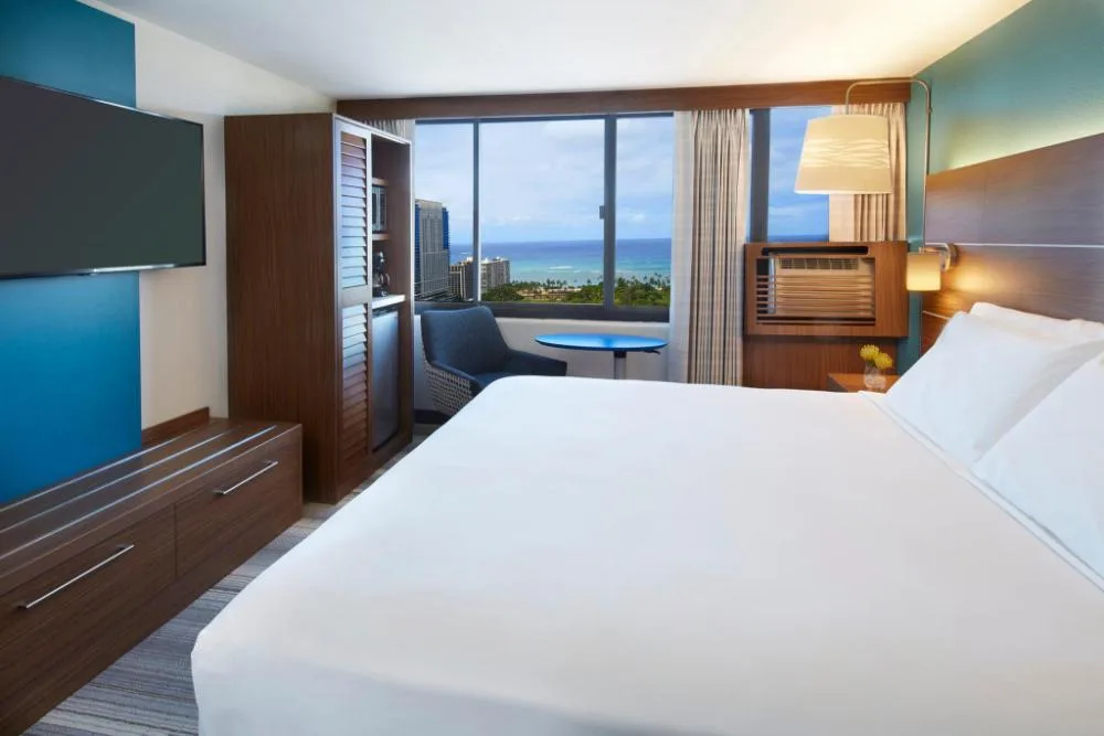 Standard room king bed with ocean view window at Holiday Inn Express Waikiki.