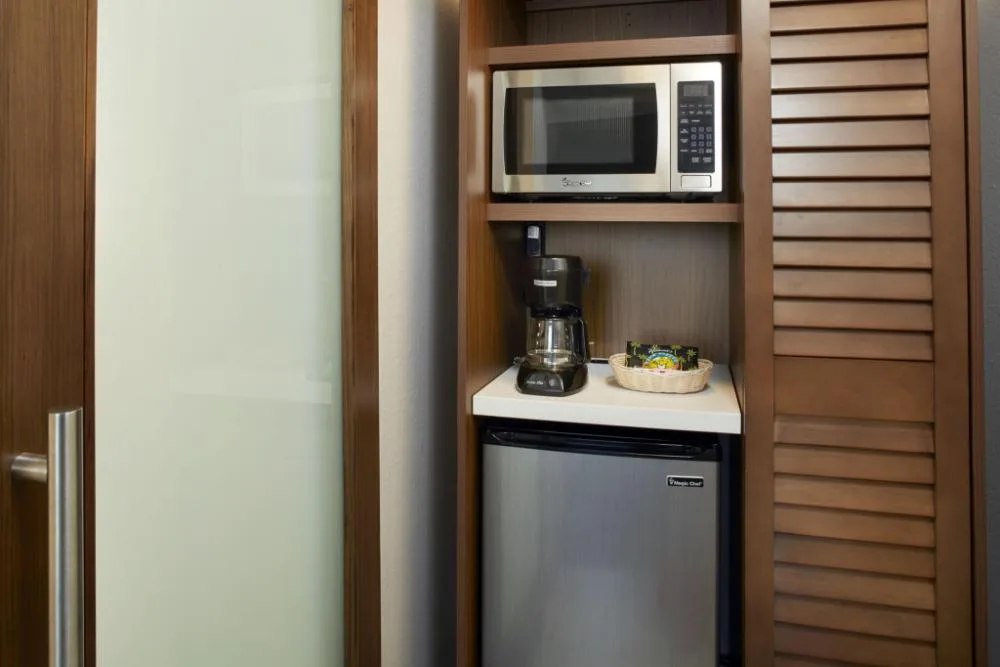 Standard room refreshment cabinet with microwave and mini fridge at Holiday Inn Express Waikiki.