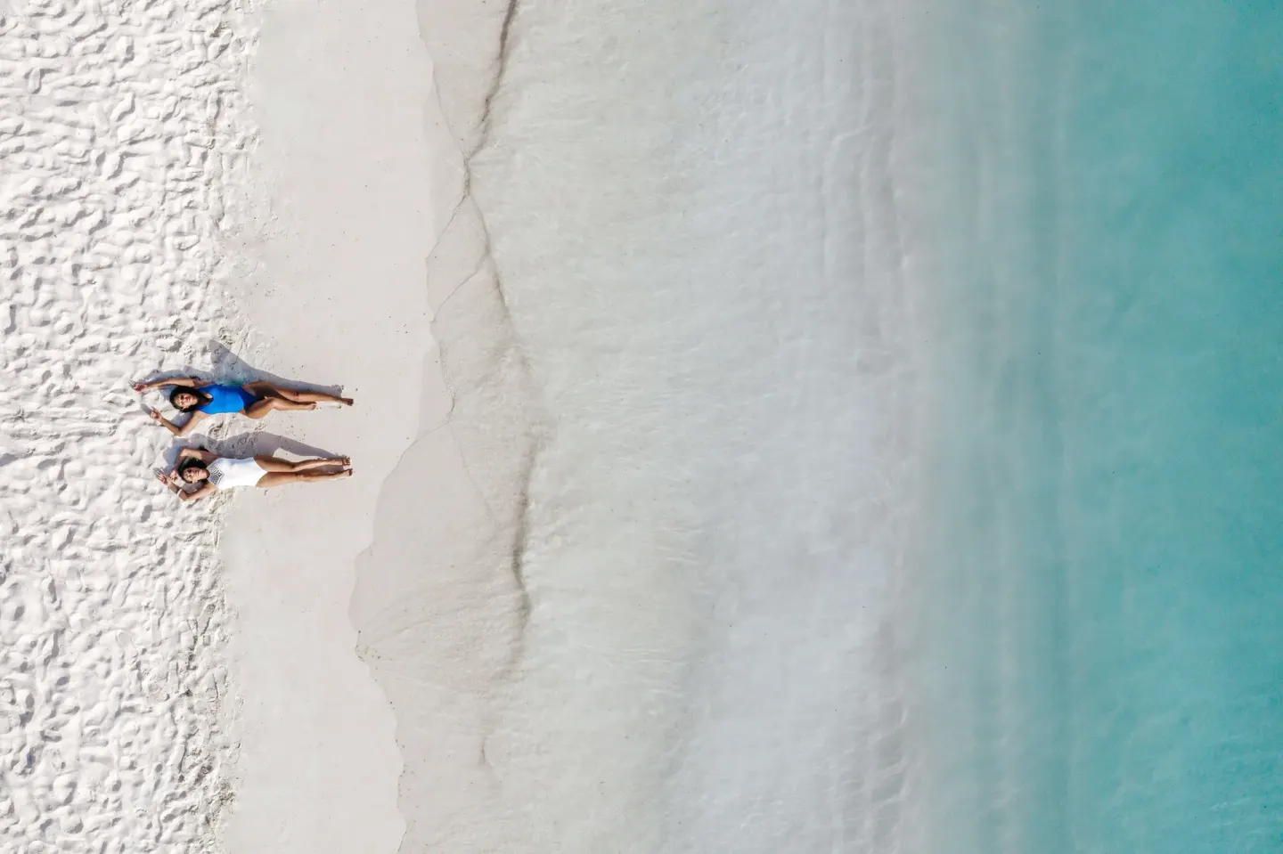 Aerial view of two guests on the beach beside turquoise water at Holiday Inn Resort Aruba - Beach Resort & Casino.