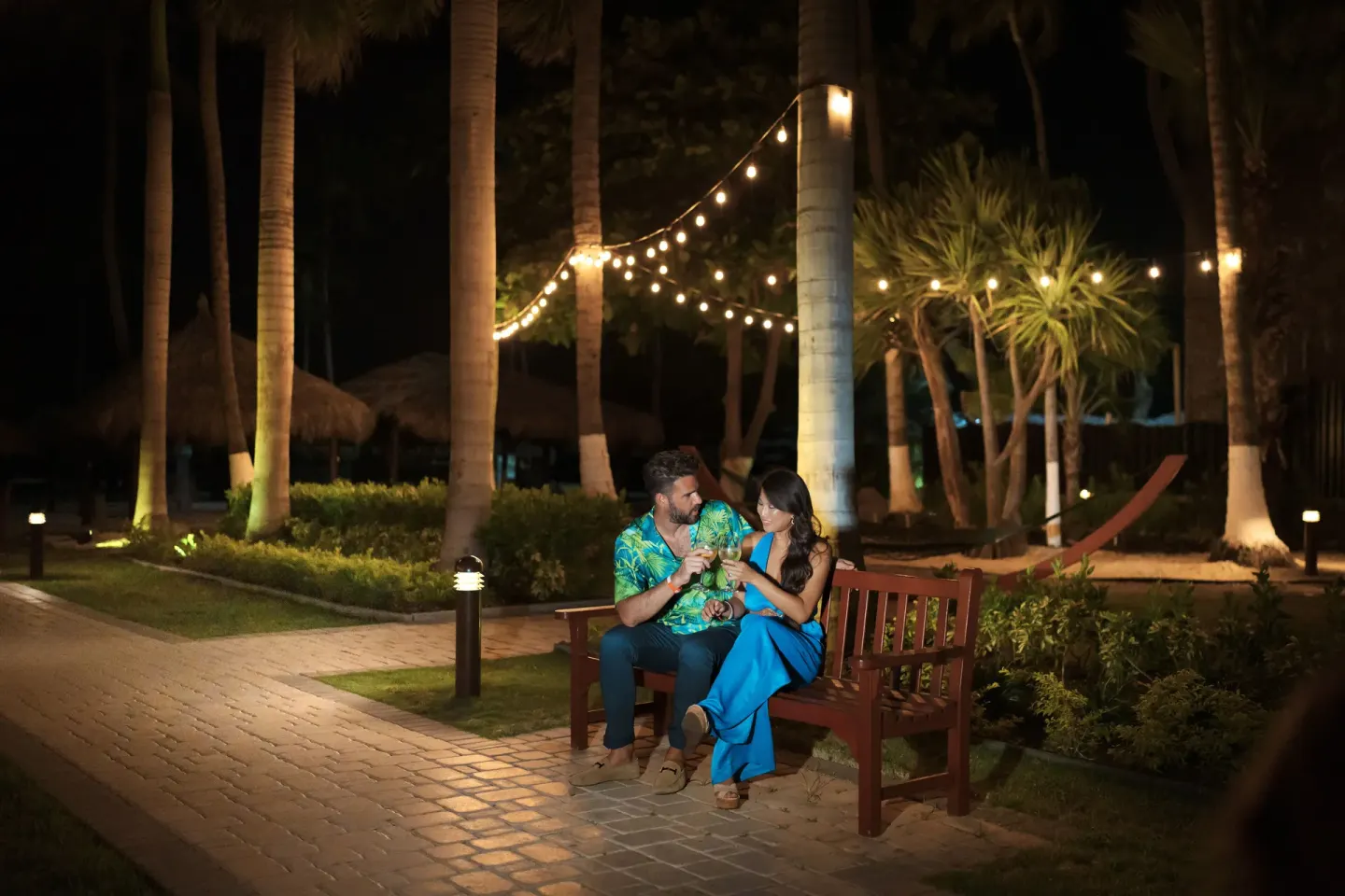 Couple seated on a lit garden bench at Holiday Inn Resort Aruba - Beach Resort & Casino.