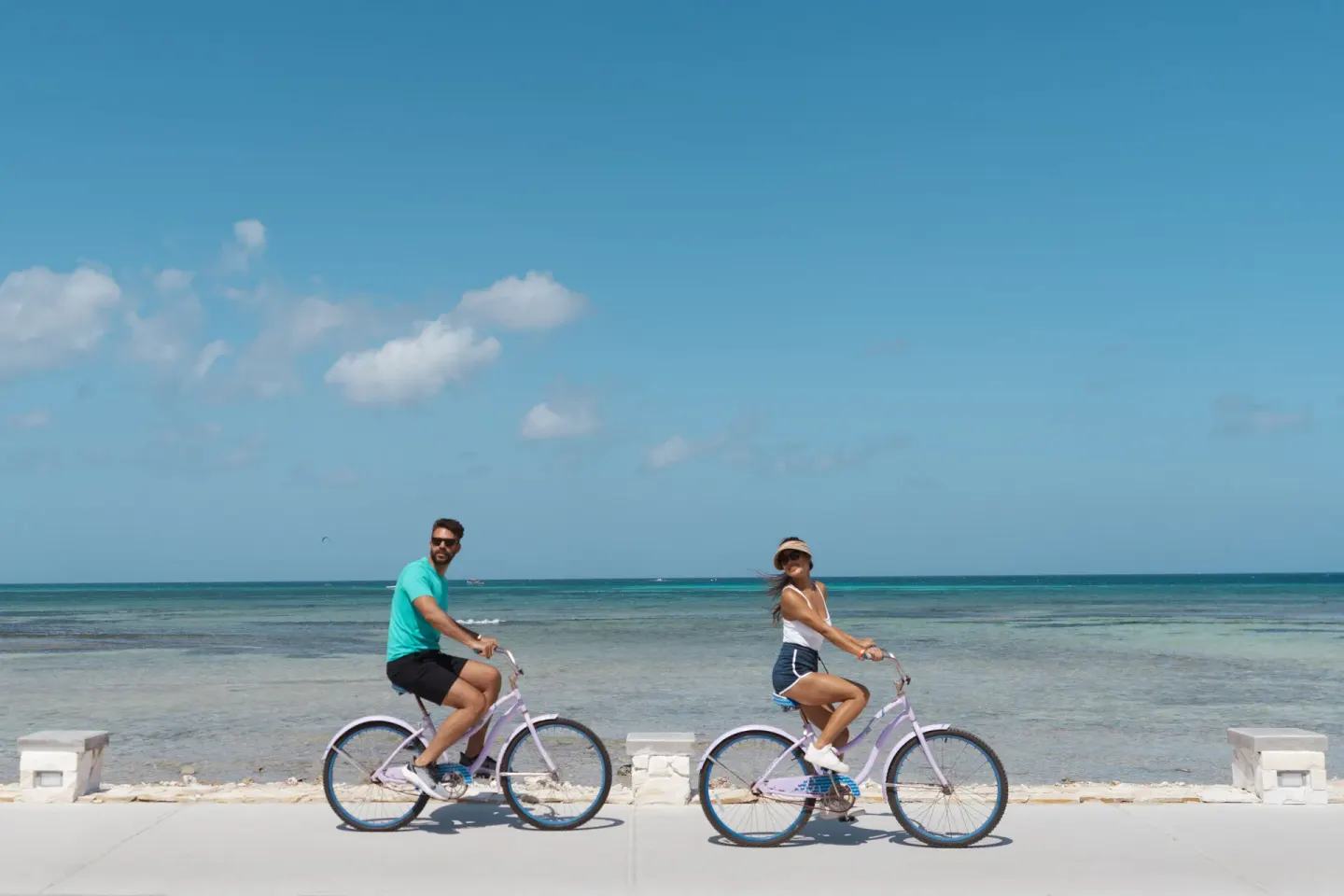 Couple riding bicycles beside the ocean at Holiday Inn Resort Aruba - Beach Resort & Casino.