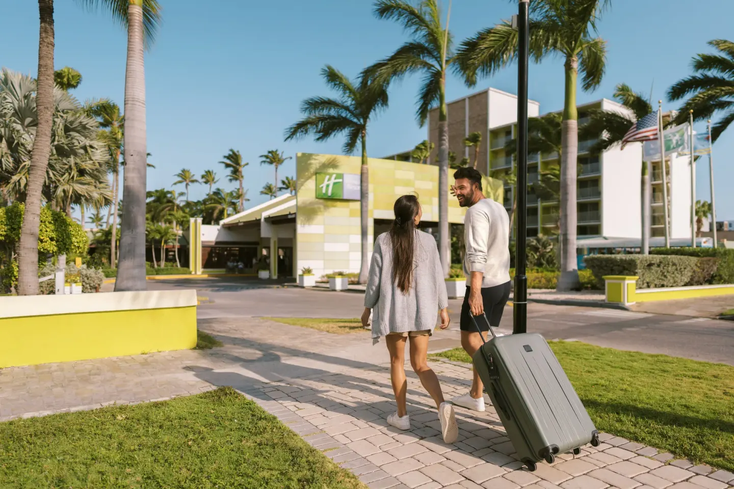 Guests with luggage walking toward the entrance of Holiday Inn Resort Aruba - Beach Resort & Casino.