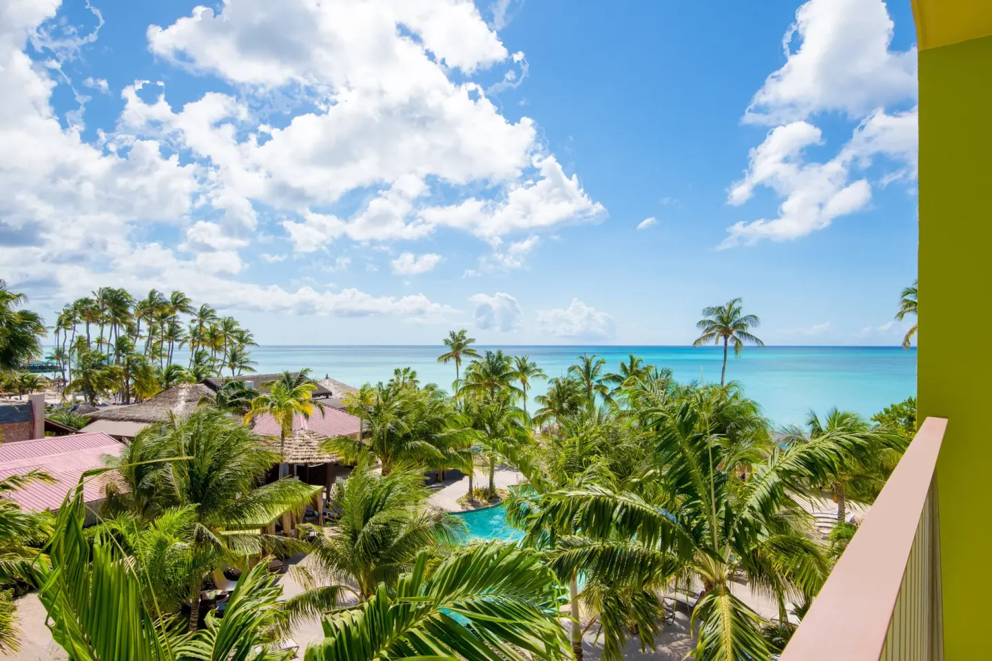 Balcony view with palms, pool, and ocean at Holiday Inn Resort Aruba - Beach Resort & Casino.