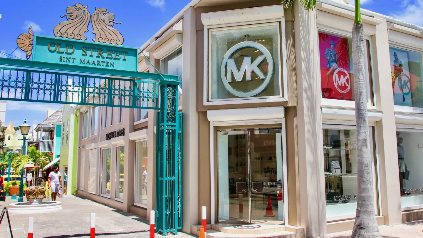 Old Street entrance near Holland House Beach Hotel with storefronts and a turquoise gate.
