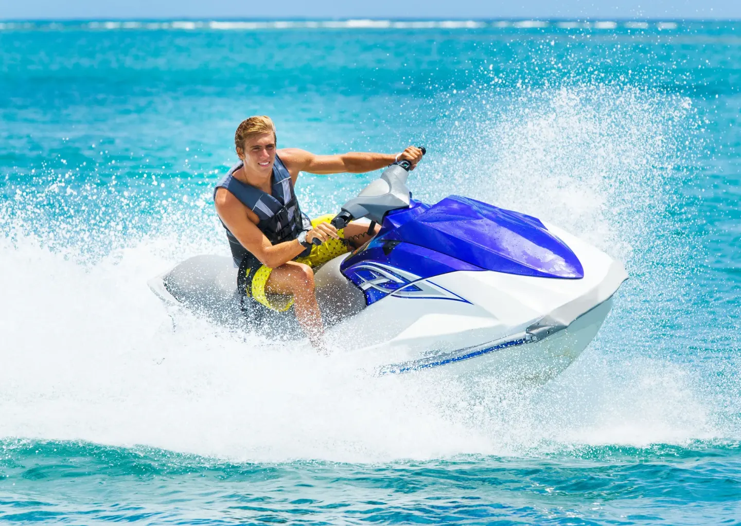 Guest riding a personal watercraft on bright blue water near Holland House Beach Hotel.