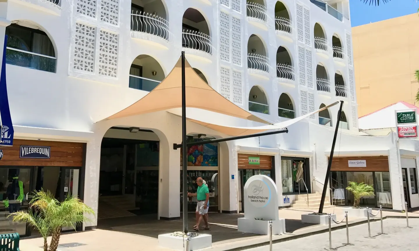 The white street-facing facade and entrance of Holland House Beach Hotel.