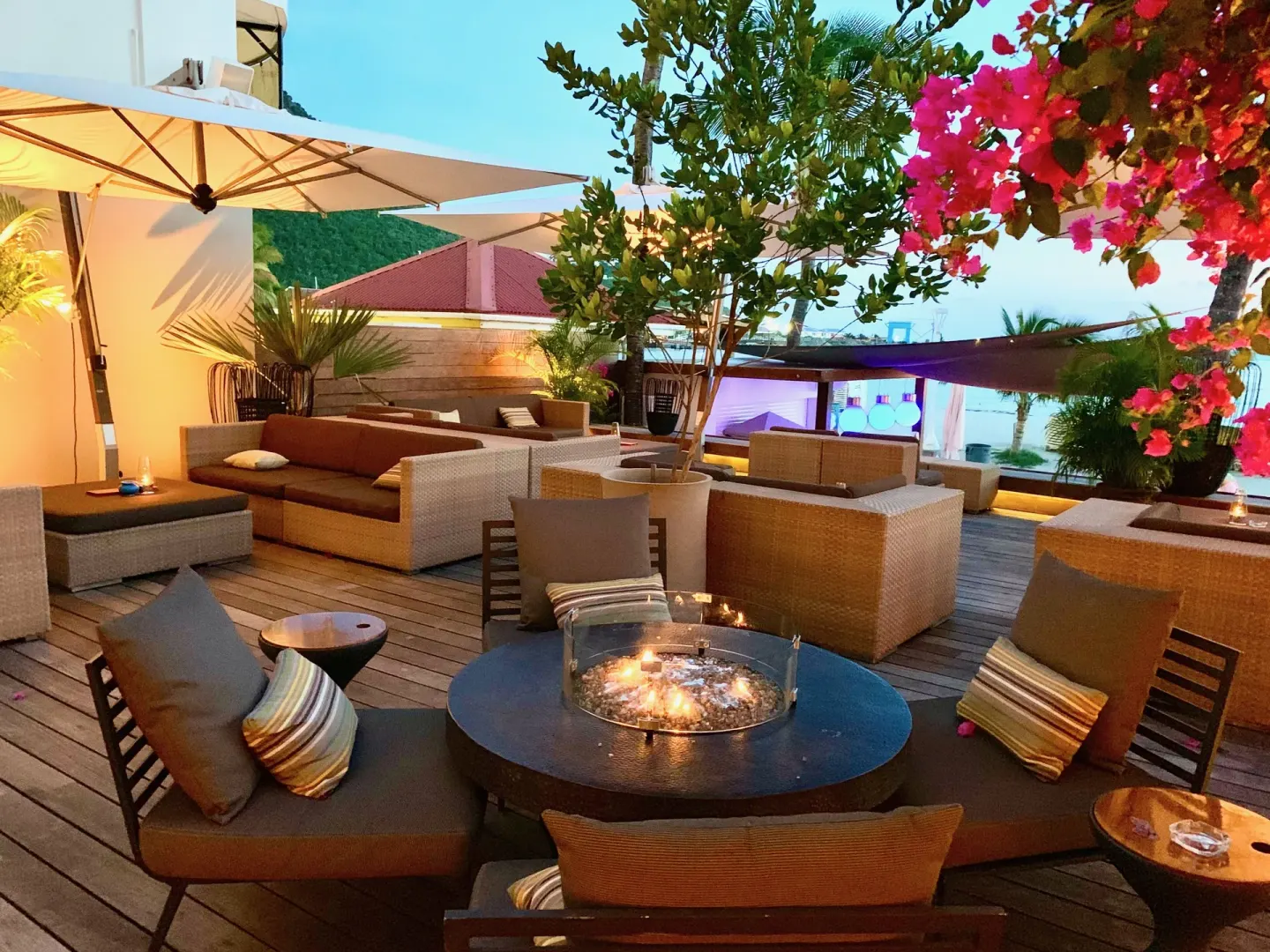 Terrace lounge with fire table and ocean glimpse at Holland House Beach Hotel.