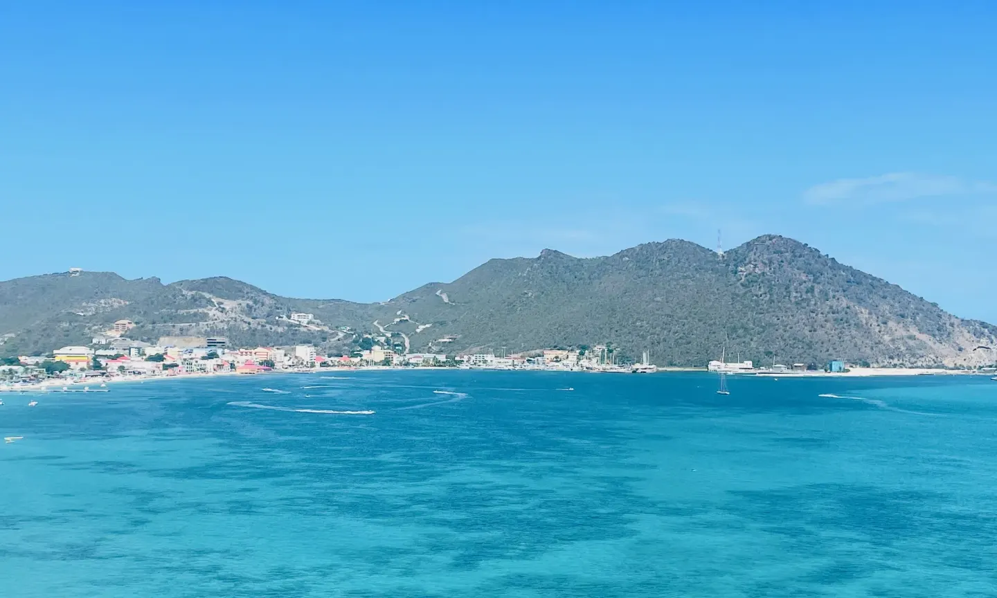 Turquoise bay water and green hills viewed from Holland House Beach Hotel.