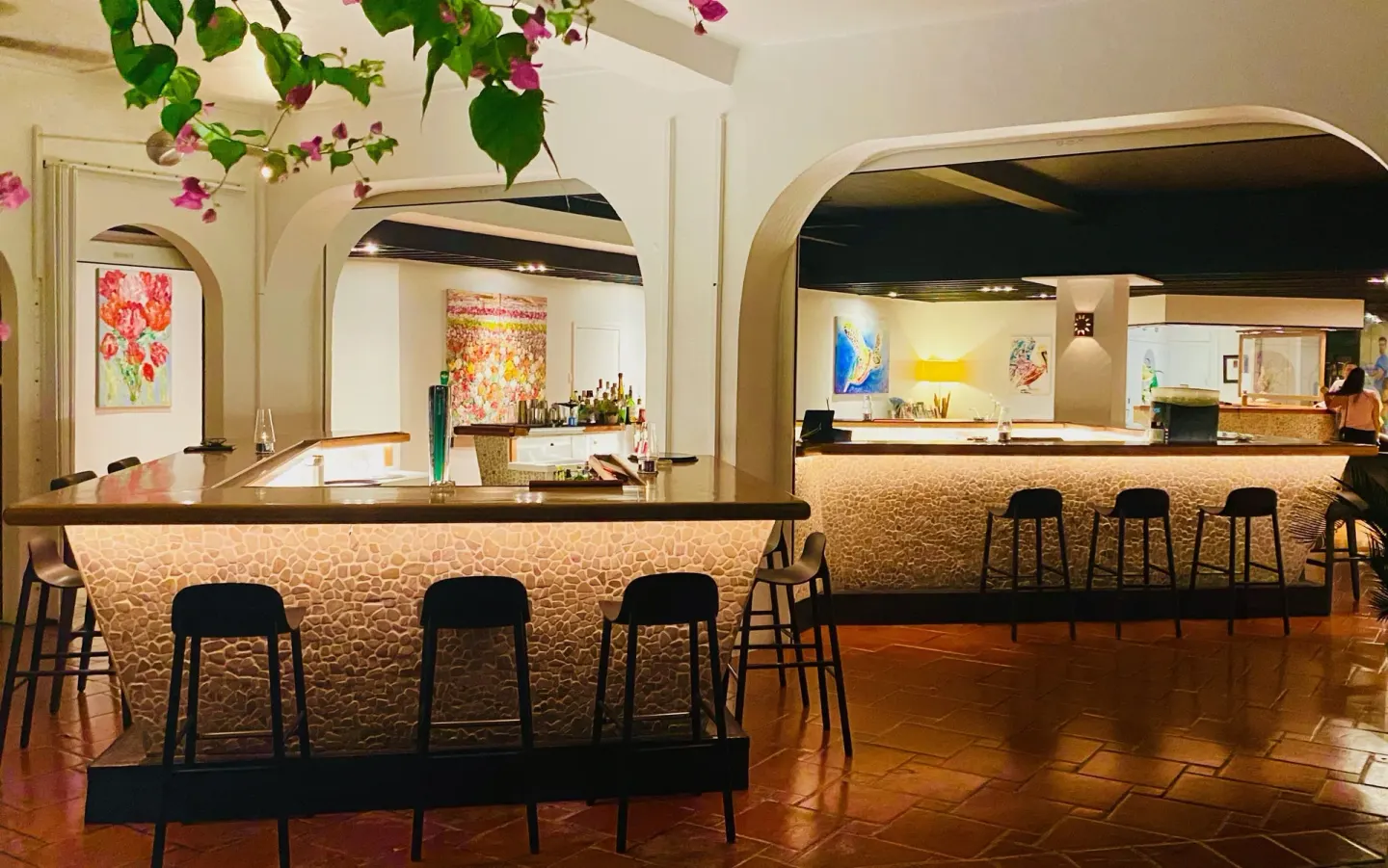 Indoor bar counters with stools sit beneath archways at Holland House Beach Hotel.