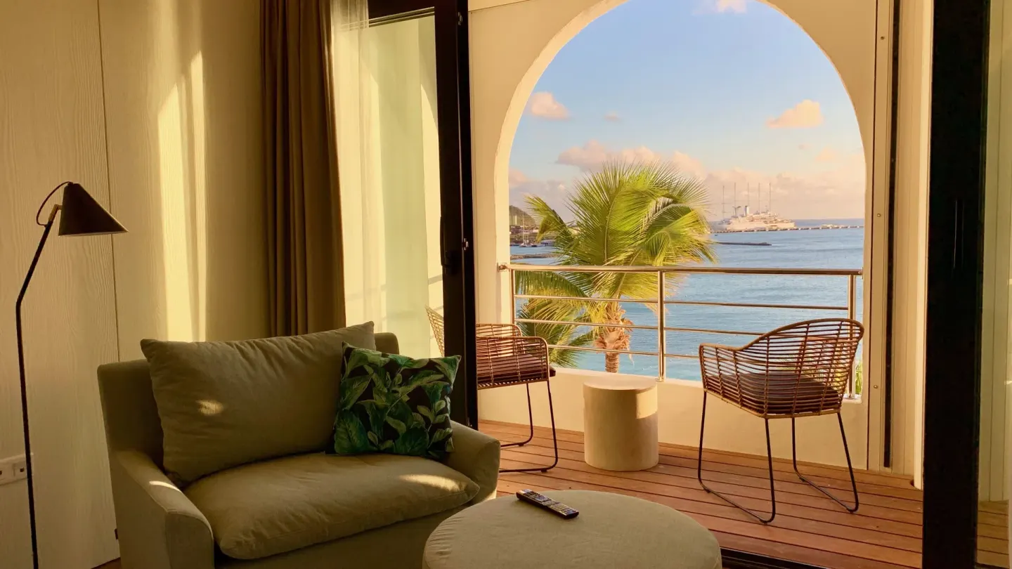 Sitting area and balcony sea view in a Deluxe room at Holland House Beach Hotel.