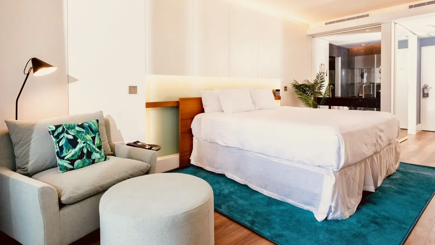 Executive Suite City View king bed and armchair at Holland House Beach Hotel.